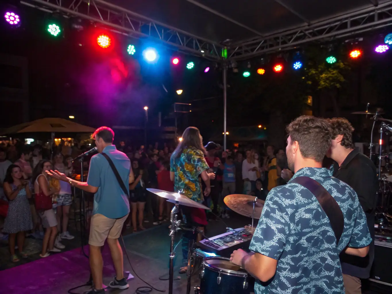 A lively band performing on stage with enthusiastic audience members clapping and dancing, showcasing BAD TRIPOUX ASSO's music support and development service.